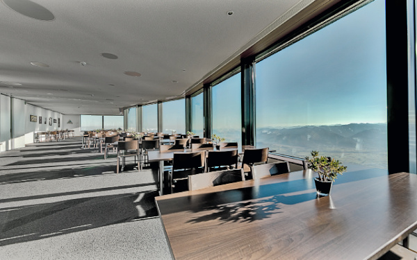 Innenansicht Panoramarestaurant mit grossen Fenstern und Holztischen und -stühlen