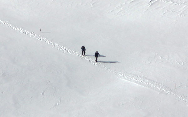 Zwei Wanderer in schneebedeckter Landschaft mit Fussspuren